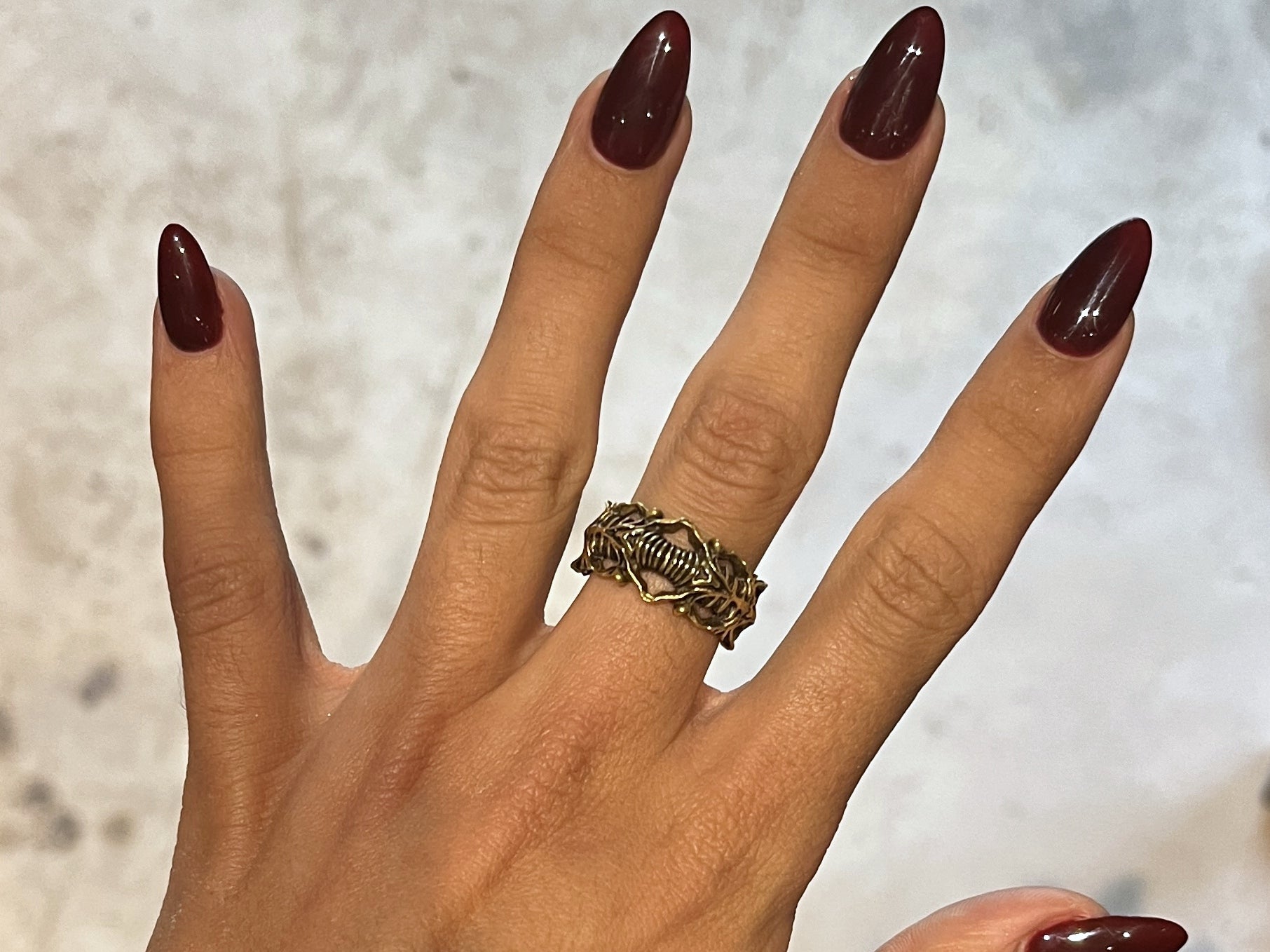 Actual BIOORGA yellow brass ring on a hand with burgundy nails, showing the ring's scale and warm patina.